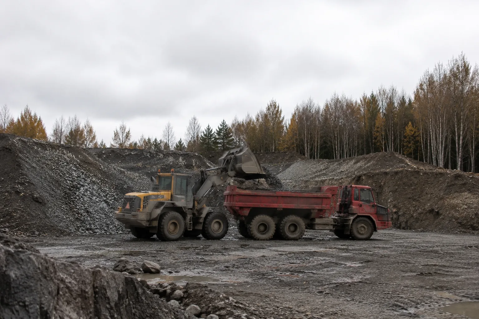 Hjullastare tippar kross i en dumper vid ett grustag.